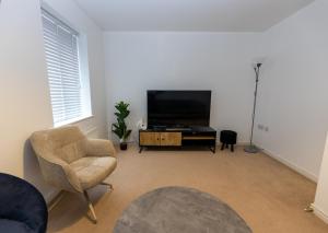 a living room with a television and a chair at Vantage Stays in Gloucestershire
