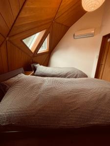 a attic bedroom with a bed with a window at ゲストハウスフォレ in Kukumo
