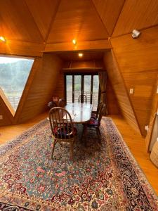 a dining room with a table and chairs on a rug at ゲストハウスフォレ in Kukumo