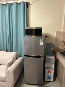 a microwave on top of a refrigerator next to a couch at Sitati in Ruaka