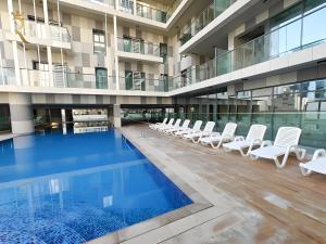 an empty pool in a building with white lounge chairs at Cozy Poolside 1BR - Serene Luxe Chic Retreat in Abu Dhabi