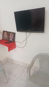 a flat screen tv hanging on a wall with a chair at Ganga Homestays in Tiruvannāmalai