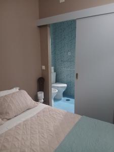 a bedroom with a bed and a bathroom with a toilet at Casa da Nonô in Coimbra