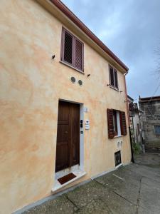 a building with a brown door and two windows at Corte 'e Susu - Domo Experience in Ortueri