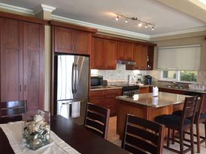 a kitchen with wooden cabinets and a stainless steel refrigerator at Hispaniola 2-Bedroom Ground Floor in Sosúa