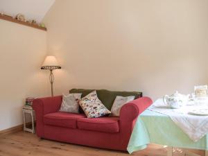 a living room with a red couch and a table at Badgers Den - Uk32084 in Dorstone