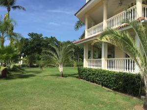 a large house with palm trees in the yard at Hispaniola 2-Bedroom Ground Floor in Sosúa
