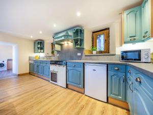 a large kitchen with blue cabinets and white appliances at Horsecroft - Uk37462 in Dorstone +29 photos
