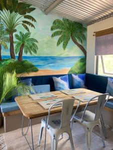 a dining room with a table and palm trees mural at The Voyager Océan View in Port Mathurin