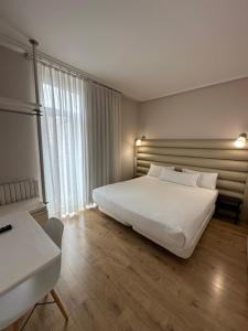 a bedroom with a white bed and a large window at Hotel Pilar Plaza in Zaragoza +94 photos