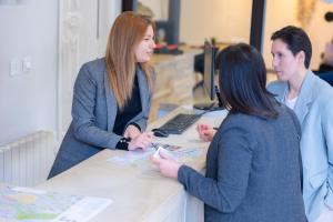a group of three women standing around a desk at Hotel Pilar Plaza in Zaragoza