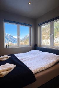 a bedroom with a large bed with two windows at Trolltunga Stay - Mountain & Waterfall View in Odda