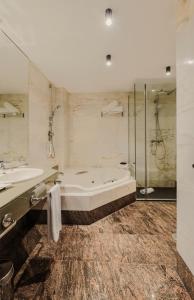 a bathroom with a tub and two sinks and a shower at Rafaelhoteles Atocha in Madrid