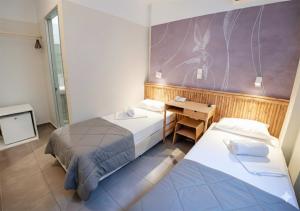 a bedroom with two beds and a desk and a wall at LUX Hotel 5 mins walk from port of Piraeus and metro station in Piraeus