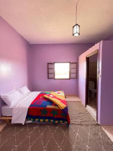 a purple bedroom with a bed and a window at Sahara desert Maison in Merzouga