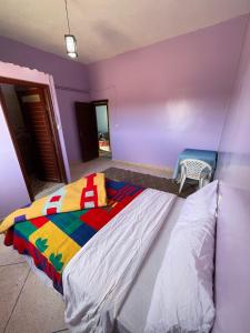 a bedroom with a colorful bed and a chair at Sahara desert Maison in Merzouga +7 photos