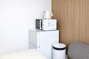 a room with a microwave on top of a refrigerator at ホテルクレイドルキャビン田無 in Nishitokyo