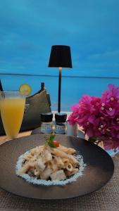 a plate of pasta on a table with a glass of orange juice at DT Beachfront Villas Hotel & Spa in Mkunguni