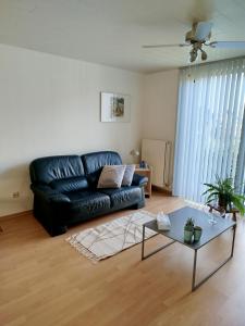 a living room with a black leather couch and a table at Aoja in Maasmechelen