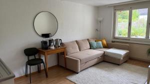 a living room with a couch and a mirror at Meiringen Retreat - Sauna, Terrace & Pinball in Meiringen