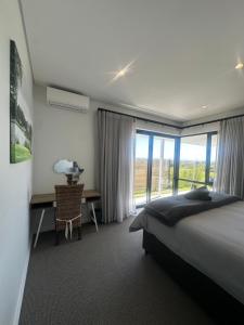 a bedroom with a bed and a desk and a window at Seabreeze Golf Retreat in St Francis Bay