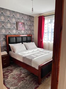 a bedroom with a large bed with a red curtain at Serenity Homes in Ruiru