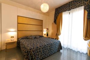 a bedroom with a bed and a large window at Hotel Ambassador in Rimini