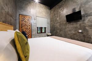 a bedroom with a white bed and a flat screen tv at Urbanview Hotel Syariah Keys Banjarmasin by RedDoorz in Terantang