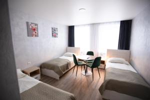 a room with three beds and a table and chairs at Dzūkija Hotel in Alytus