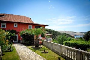 a red house with a fence and a tree in the yard at Apartments in Lopar - Insel Rab 36282 in Lopar