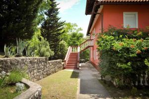 a red house with a staircase next to a garden at Apartments in Lopar - Insel Rab 36282 in Lopar