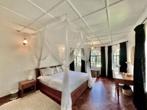 a bedroom with a white bed with a canopy at Hornbill Cottage in Nairobi