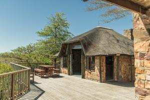 a cabin with a deck with a thatched roof at Intaba Lodge in Kirkwood