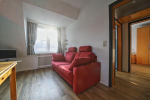 a living room with a red couch and a television at Appartement-8 in Süddorf