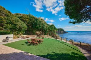 a picnic table and chairs on a lawn next to the ocean at UMIBE IseShima in Shima