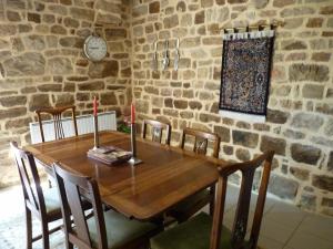 a wooden table in a room with a stone wall at La Longere in Lonlay-lʼAbbaye