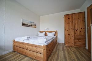 a bedroom with a wooden bed and a wooden door at Appartement-6 in Süddorf