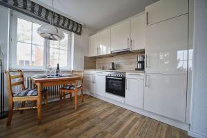 a kitchen with white cabinets and a table and a dining room at Appartement-7 in Süddorf +8 photos