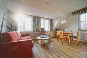 a living room with a couch and a table and chairs at Appartement-5 in Süddorf