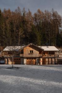 a large wooden house with snow on the ground at Agriturismo La Daga Nature Lodge in Auronzo di Cadore