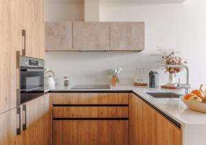 a kitchen with wooden cabinets and a bowl of fruit at Upon Harbor - Seixal Bay Hotel in Seixal