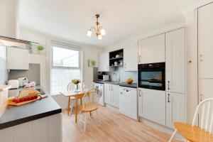 a kitchen with white cabinets and a table and chairs at 2 Bed in Seaton oc-mbbri in Seaton