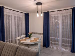 a dining room with a table and blue curtains at Apartament Honoratka in Jelenia Góra