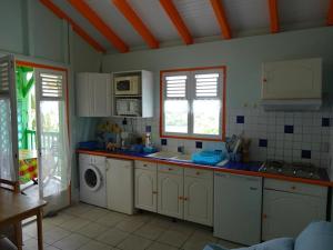 a kitchen with white cabinets and a washing machine at Les Gites Josiane in Les Trois-Îlets