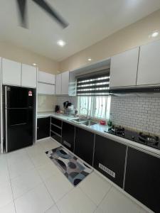 a kitchen with white cabinets and a black refrigerator at Afiq's Homestay, Manjung in Seri Manjung