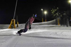 a person snowboarding down a snow covered slope at night at Hotel Habsburg in České Hamry