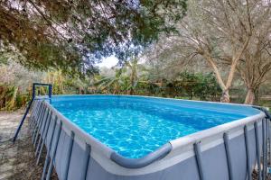 a large blue pool with trees in the background at Stunning 2BR Villa with Pool in Mġarr