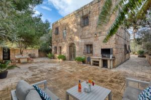 a stone building with a stone courtyard with a table at Stunning 2BR Villa with Pool in Mġarr