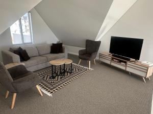 a living room with a couch and two chairs and a television at Seabreeze Golf Retreat in St Francis Bay