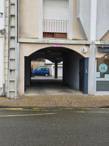 a parking garage with a blue car under a building at ''Coccinelle'' WIFI - CENTRE - MODERNE in Dax